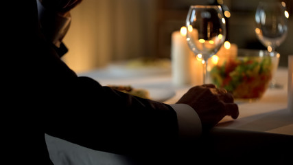 Nervous aged man in suit waiting date at restaurant table, romantic tradition