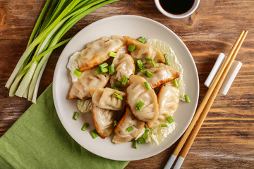 Plate with tasty Japanese gyoza on wooden table
