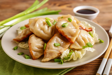 Plate with tasty Japanese gyoza on wooden table, closeup