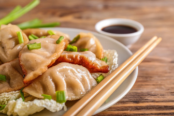 Plate with tasty Japanese gyoza on wooden table, closeup
