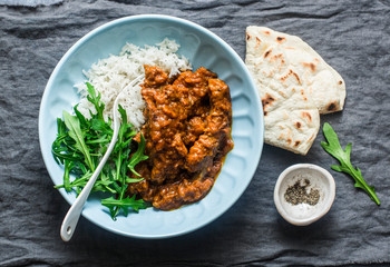 Pork ribs curry with rice, arugula and tortillas on grey background, top view. Delicious Indian style lunch