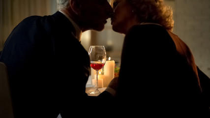 Senior man and woman kissing during romantic date, married couple affection