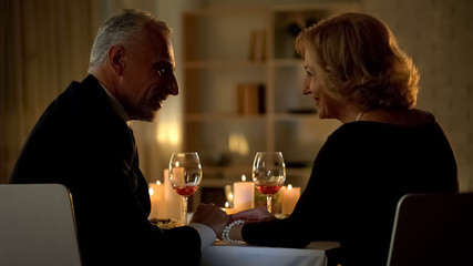 Beautiful aged lady looking at man, couple relaxing in restaurant, romantic date