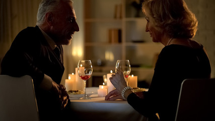 Senior woman and man flirting in restaurant, love feelings, aged couple romance