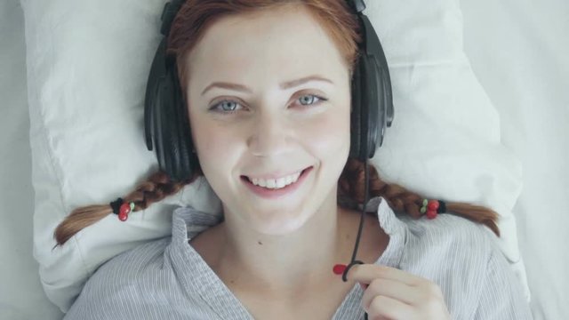 Young foxy woman listen to music with headphones laying down in bed