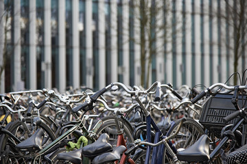 Lots of bicycles parked in front of a modern office business building
