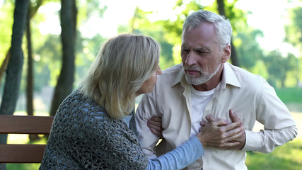 Sad retired man feeling heart pain, cardio problems, wife supporting husband