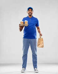 service and people concept - happy indian delivery man with food in bag and drinks in blue uniform over grey background