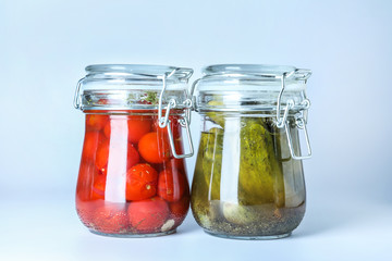 Glass jars with fermented vegetables on white background