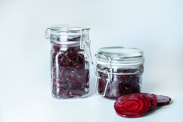 Glass jars with fermented beetroot on white background