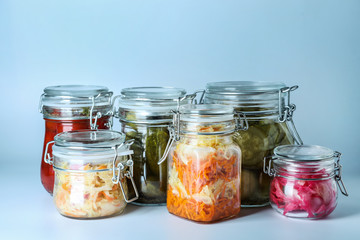 Glass jars with fermented vegetables on white background