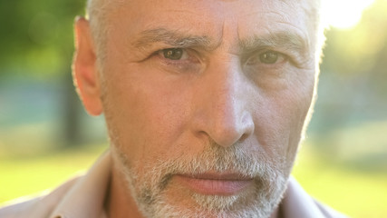 Bearded man in his 70s thinking about future and looking into camera, closeup