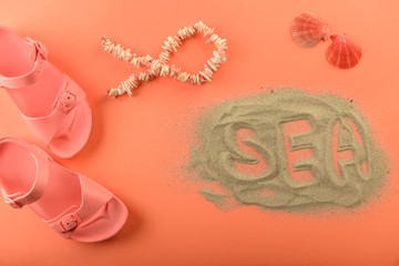 Summer composition with word SEA and beach accessories on coral background