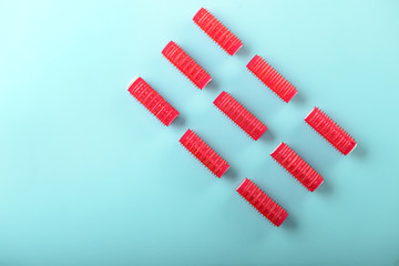 Hair curlers on color background