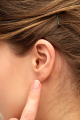 health, people and beauty concept - close up of young woman pointing finger to her ear