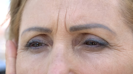 Aged woman touching her wrinkled skin, nostalgic memories, anti-aging cosmetics