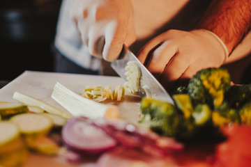 Obraz na płótnie Canvas Cook cutting broccoli with a knife on the board