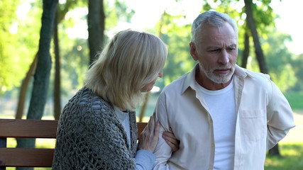 Fototapeta premium Healthcare, retired man suffering sharp back pain, sitting on bench in park