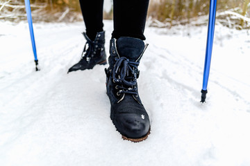 Active female hiking in winter, walking in snow, legs and boots view. Trekking outdoors in nature....