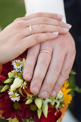 Obraz na płótnie Canvas Hands of bride and groom with flower bouquet