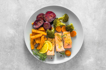 Gourmet dinner with cooked salmon and vegetable. Healthy food on plate with vegetables and fish fillet, top view.