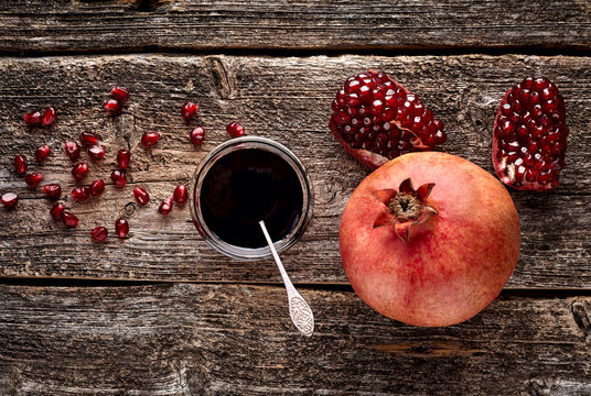 Homemade pomegranate jam in a glass saucer  with a spoon, fresh open pomegranate on a wooden background, selective focus - Image