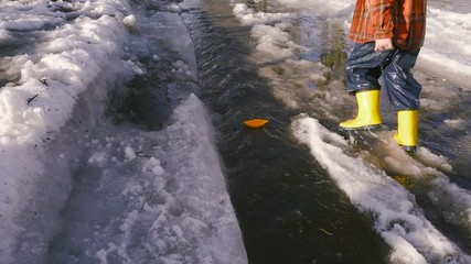 boy launches a paper boat at the spring creek