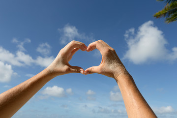 Female hands in front of blue sunny sky, vacation concept