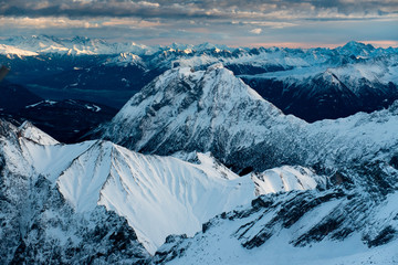 Scenic aerial view of snowy Zugspitze mountains and sunset sky in Bavarian Alps, Germany.
