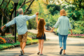 Happy healthy family walk together on path in the park in summer. Concept of family bonding.