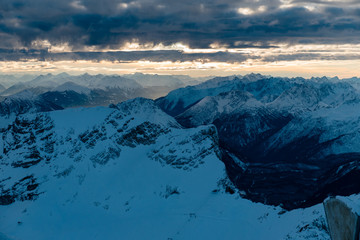 Scenic aerial view of snowy Zugspitze mountains, hills and valley on sunset in Bavarian Alps, Germany.