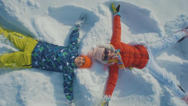 Mother and son making angels in the snow and having fun