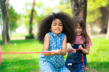 Happy children playing tug of war and having fun during summer camping in the park. Children...