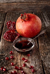 Homemade pomegranate jam in a glass saucer  with a spoon, fresh open pomegranate on a wooden...