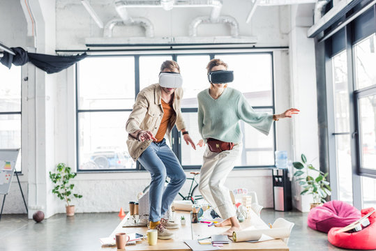 female and male architects wearing vr headset, gesturing with hands and having virtual reality experience in loft office