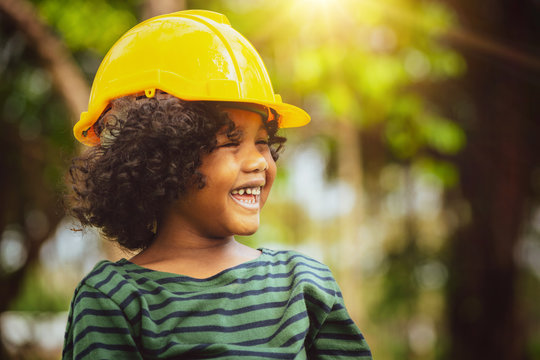 Happy little boy engineer wearing yellow safety helmet hard hat and laughing with happiness. Education and learning concept.