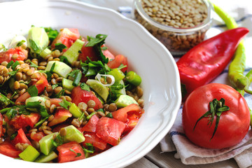 Plate with delicious lentils salad on wooden table