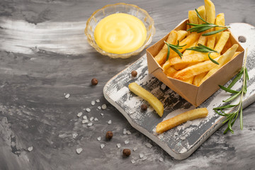 French fries with rosemary and cheese sauce on a dark background. Delicious and harmful food