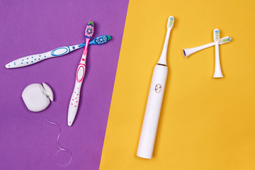 Manual and electric toothbrushes on pink coral background. Dental care