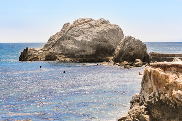 People swim around the rocks.