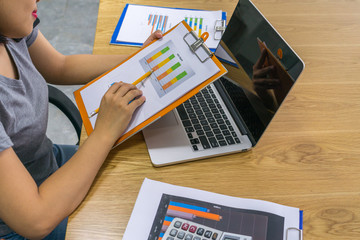 Close-up of woman hand holding pencil pointing at sales report