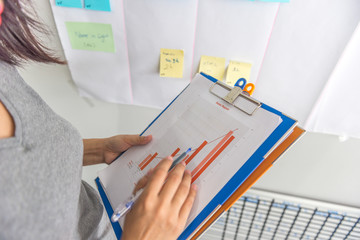 Woman hand holding pen pointing at the sales reports