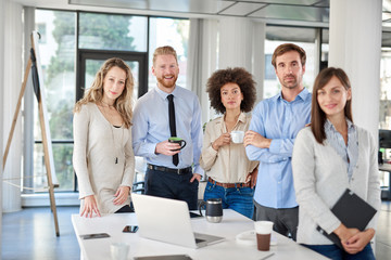 Small group of business people standing and posing at office. Start up business concept. Multi ethnic goroup. - obrazy, fototapety, plakaty