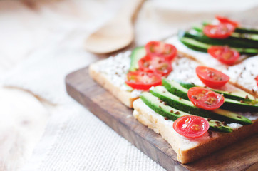 Cutting board with toasts with avocado and cherry tomatoes.
