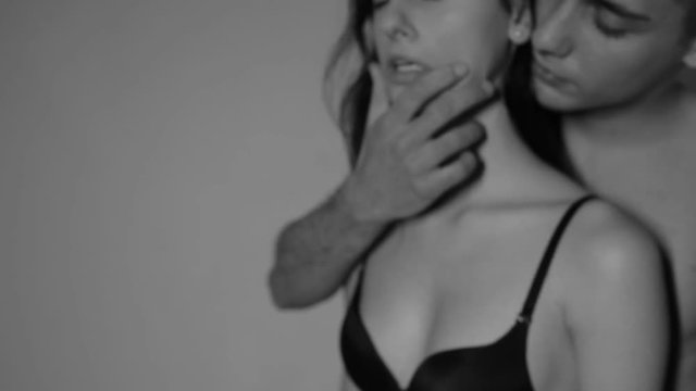 A man with a girl in the studio on a gray background. Black and white video.