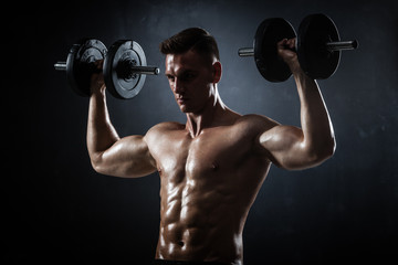 Athletic shirtless young male fitness model with dumbbells