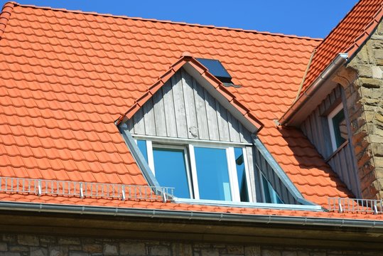 Neu renovierte Dachgauben mit Holzplanken-Verkleidung als Wetterschutz an einem denkmalgeschützten Wohngebäude