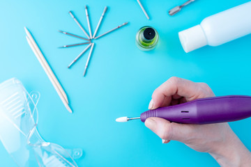 Female manicurist doing a professional manicure hardware using milling cutter on the background of...