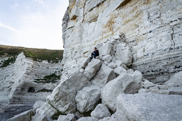 Man sitting on broken rocks of a cliff near Etretat