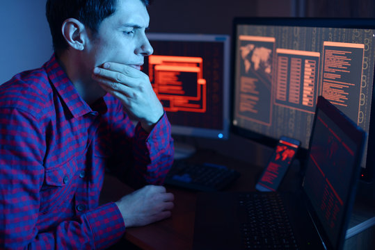 Hacker thinking about the problem of hacking on the background of screens with codes in neon light